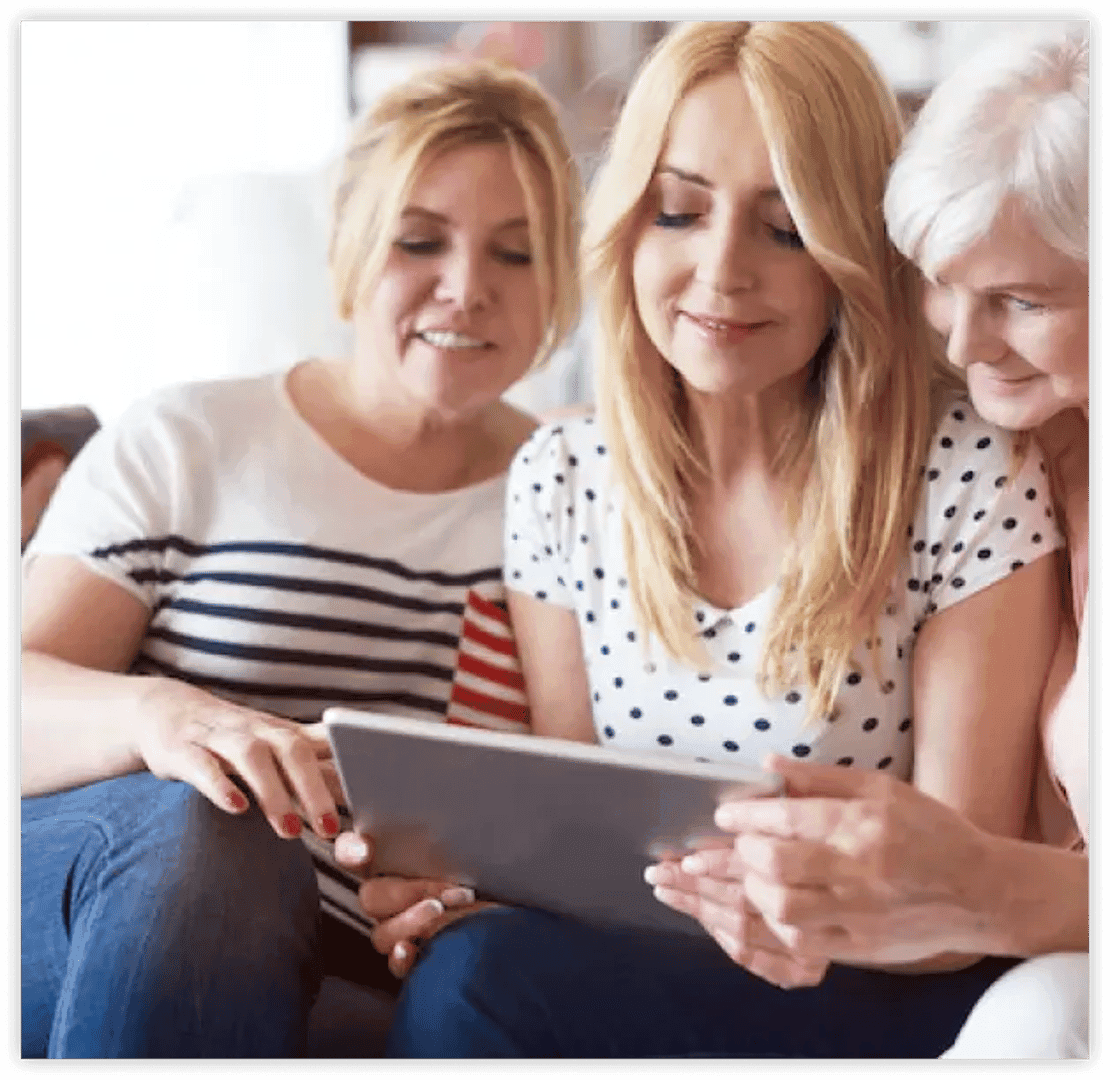 a group of 3 womens sitting on a couch holding a tablet using social media