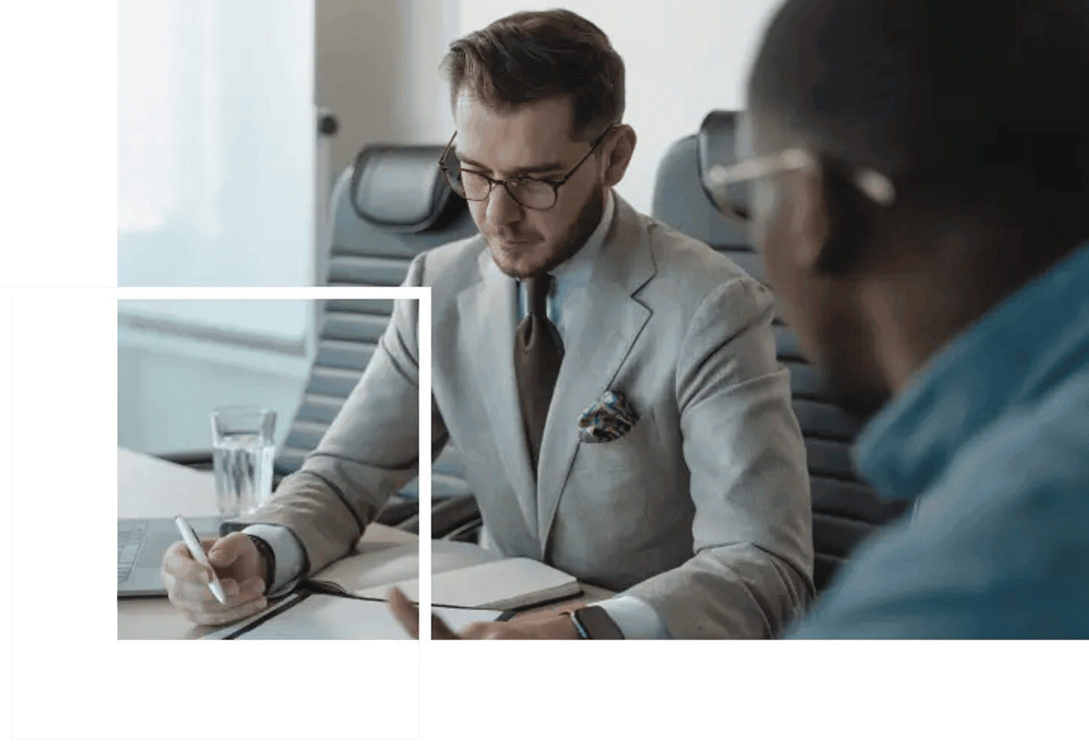 two men sitting on a table signing a contract