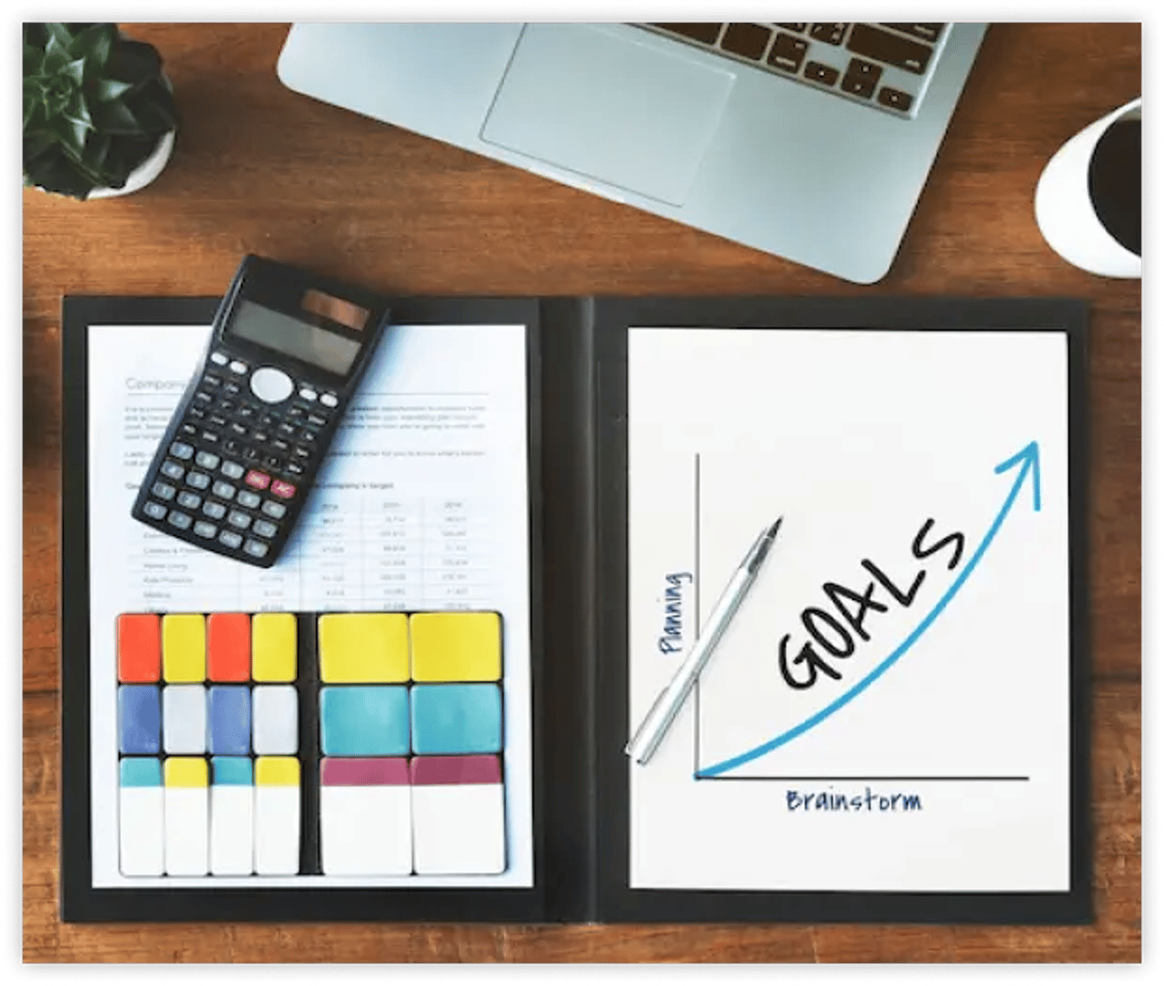 a laptop and a calculator on a table with goal's growth chart